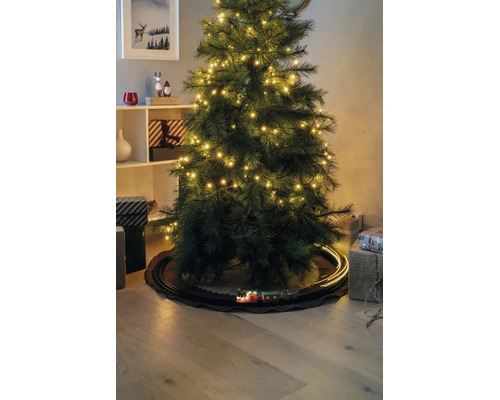 Kunstkerstboom met LED-lampjes en een speelgoedtrein op rails eronder, omringd door cadeaus.