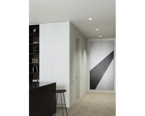 Moderne gangverlichting met drie inbouwspots in het plafond, minimalistische inrichting met groot kunstwerk op de muur.