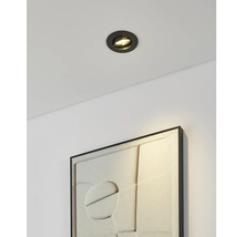 Inbouwspot in het plafond verlicht een ingelijst kunstwerk met textuur aan een muur.
