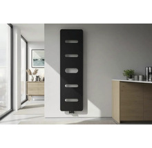 Moderne verticale designradiator in zwart met horizontale uitsparingen aan een witte muur in een lichte minimalistische kamer.