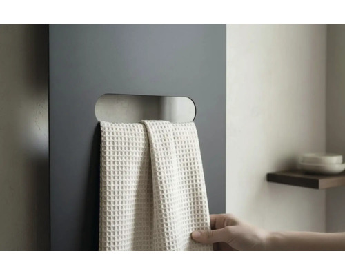 Donkergrijze vlakke radiator met horizontale uitsparing als handdoekhouder en een lichte handdoek met wafelstructuur.