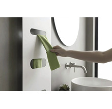 Hand pakt een groene handdoek uit een witte designradiator in een moderne badkamer met wastafel en kraan.