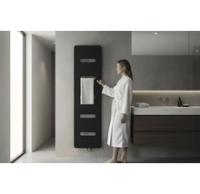 Moderne badkamer met zwarte designradiator aan de wand, een vrouw in een witte badjas en een wastafelmeubel met donkere onderkast.
