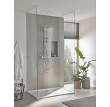 Moderne inloopdouche met glazen wand, chromen regendoucheset en vlakke douchebak in een lichte badkamer met planten.