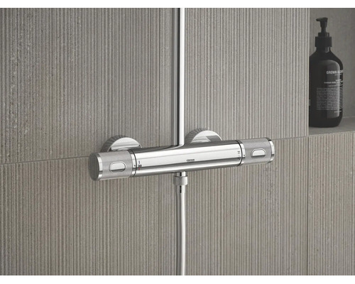 Grohe douchethermostaat van chroom met twee gestructureerde grepen en 38 graden markering gemonteerd op een getegelde wand.