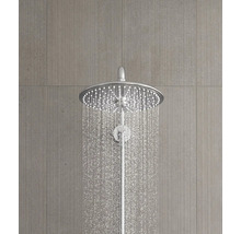 Ronde chromen regendouchekop met stromend water op een grijze tegelwand met textuur.