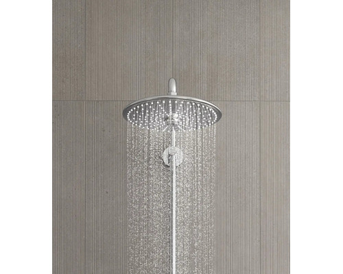 Ronde chromen regendouchekop met stromend water op een grijze tegelwand met textuur.