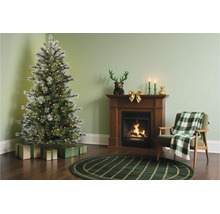 Sfeervol ingerichte woonkamer met verlichte kunstkerstboom, haard, fauteuil met geruite deken en kerstversiering.