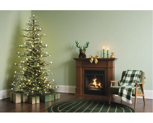 Feestelijk ingerichte woonkamer met verlichte kerstboom, cadeaus, houten open haard met brandend vuur en een fauteuil met geruite deken.