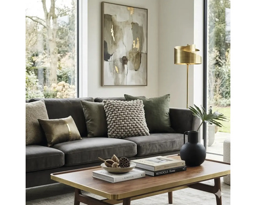 Lichte woonkamer met grijze bank, sierkussens, houten salontafel met gouden rand, gouden vloerlamp en abstract schilderij.
