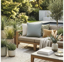 Lichte buitenlounge met houten bank, diverse sierkussens, een deken en vele potplanten op een stenen terras naast een zwembad.