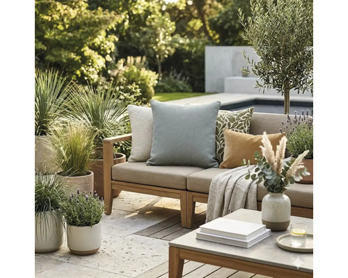 Lichte buitenlounge met houten bank, diverse sierkussens, een deken en vele potplanten op een stenen terras naast een zwembad.