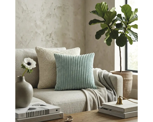 Moderne woonkamer met een mintgroen corduroy kussen en een beige gebreid kussen op een neutrale stoffen bank.