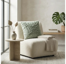 Heldere woonkamer met moderne loungefauteuil van bouclé, sierkussen met patroon, plaid en bijzettafel met steenlook.