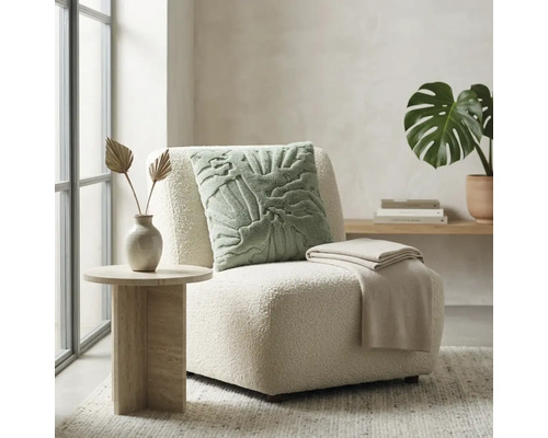 Heldere woonkamer met moderne loungefauteuil van bouclé, sierkussen met patroon, plaid en bijzettafel met steenlook.