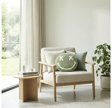 Lichte woonkamer met houten fauteuil, rond groen smiley-kussen, bijzettafel en kamerplant voor een raam met gordijnen.