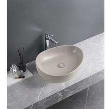 Ovale opzetwastafel in mat beige op een werkblad met marmerlook en een chromen kraan.
