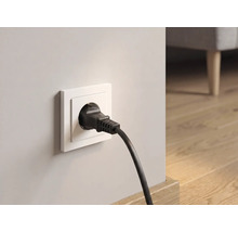 Zwarte randaardestekker in wit stopcontact in een lichte kamer met houten vloer.