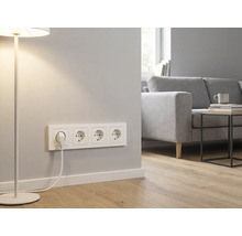 4-voudige wandcontactdoos met randaarde in een lichte, moderne woonkamer met bank, bijzettafel en vloerlamp.