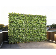 Kunstmatige plantenwand als privacy-scherm op een terras met tegels en reling.