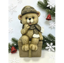 Kerstfiguur teddybeer zittend op een geschenkdoos met muts en sjaal.