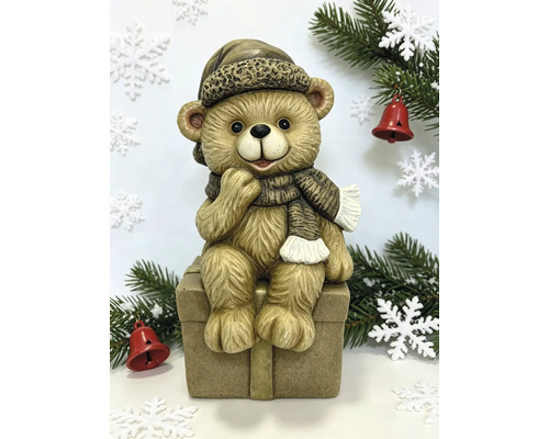 Kerstfiguur teddybeer zittend op een geschenkdoos met muts en sjaal.