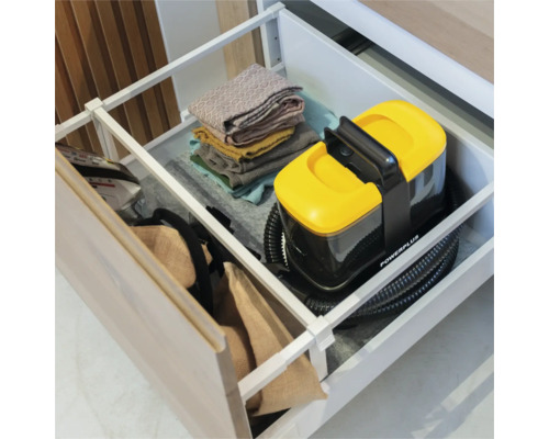 Compacte Powerplus tapijtreiniger georganiseerd opgeborgen in een lade met gevouwen handdoeken. Powerplus Logo.