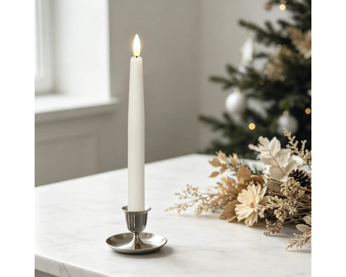 Witte led-tafelkaars in een zilveren houder op een marmeren tafel met feestelijke kerstdecoratie en een wazige kerstboom op de achtergrond.