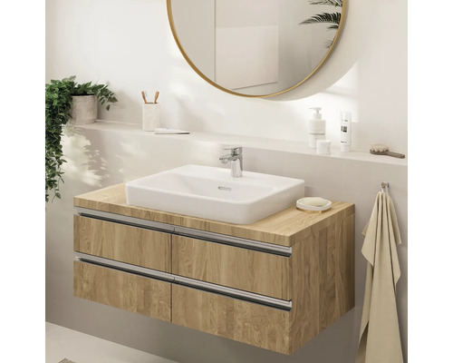 Moderne badkamer met een zwevend wastafelmeubel in houtlook, witte opbouwwastafel, chromen kraan en een grote ronde spiegel.