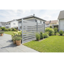Modern horizontaal lamellenhekwerk in een verzorgde tuin met terras, gazon en plantenbakken.