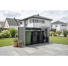Moderne grijze afvalcontainer ombouw van composiet op een terras in een georganiseerde tuin met woonhuizen op de achtergrond.