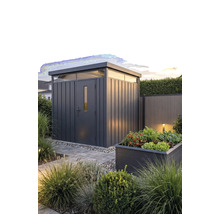 Modern metalen tuinhuis met plat dak en bovenlichten in een aangelegde tuin met een plantenbak en stenen pad.