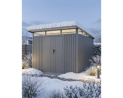 Moderne grijze metalen berging met lessenaarsdak, bovenlichten en dubbele deur in een besneeuwde tuin.