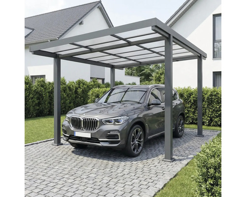 Moderne aluminium carport met lichtdoorlatend dak boven een voertuig op een geplaveide oprit bij een huis.