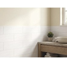 Lichte badkamer met witte rechthoekige wandtegels in halfsteensverband, een houten wastafelmeubel met stenen blad en een waskom.