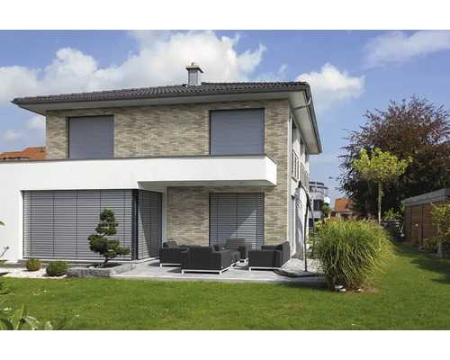 Modern woonhuis met buitenjaloezieën en rolluiken voor de ramen en een terras met tuinmeubilair en een verzorgd gazon.