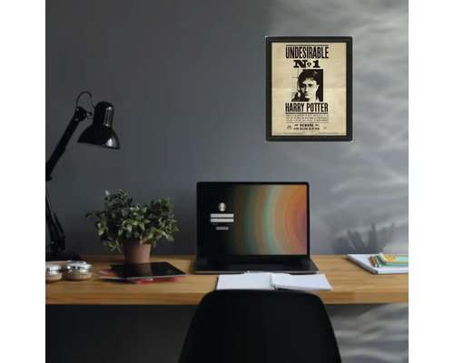 Ingelijste Harry Potter poster Undesirable nummer 1 aan een grijze muur boven een georganiseerd houten bureau met laptop en lamp.