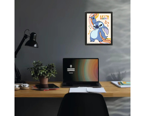 Ingelijste poster met Disney-personage Stitch en tekst Let's Dance boven een bureau met laptop en lamp in een modern ingerichte werkkamer.