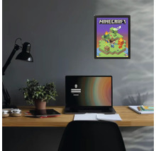 Minecraft poster in een zwarte lijst aan een donkere muur boven een bureau met een laptop en een plant.