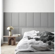 Moderne slaapkamer met rechthoekige, gewatteerde wandpanelen, een bed met wit beddengoed en een bijtafeltje met gouden lamp.