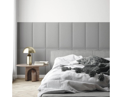 Moderne slaapkamer met rechthoekige, gewatteerde wandpanelen, een bed met wit beddengoed en een bijtafeltje met gouden lamp.