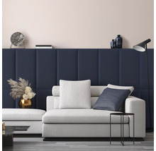 Moderne woonkamer met donkerblauwe gestoffeerde wandpanelen, een lichtgrijze bank met kussens, een zwarte bijzettafel en een vloerlamp.