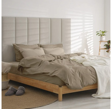 Moderne slaapkamer met houten bed, gecapitonneerd paneel-hoofdbord, taupekleurig beddengoed en witte sprei op een rond jute tapijt.