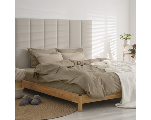 Moderne slaapkamer met houten bed, gecapitonneerd paneel-hoofdbord, taupekleurig beddengoed en witte sprei op een rond jute tapijt.