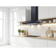 Moderne, lichte keuken met een zwarte wandschouw afzuigkap boven een inductiekookplaat, witte metrotegels en een houtlook aanrechtblad.