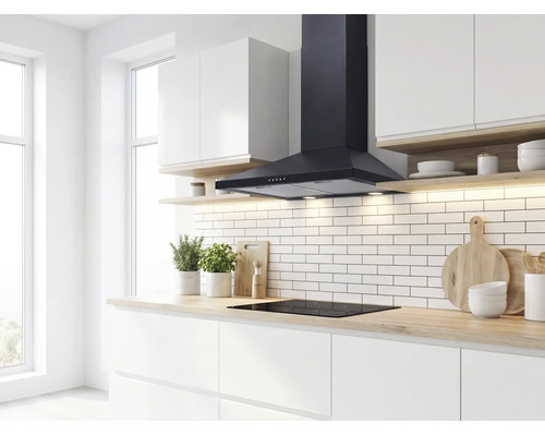 Moderne, lichte keuken met een zwarte wandschouw afzuigkap boven een inductiekookplaat, witte metrotegels en een houtlook aanrechtblad.
