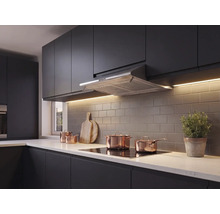 Moderne keuken met donkere fronten, roestvrijstalen afzuigkap, inductiekookplaat, koperen pannen en een tegelwand.