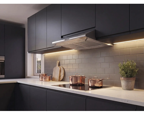 Moderne keuken met donkere fronten, roestvrijstalen afzuigkap, inductiekookplaat, koperen pannen en een tegelwand.