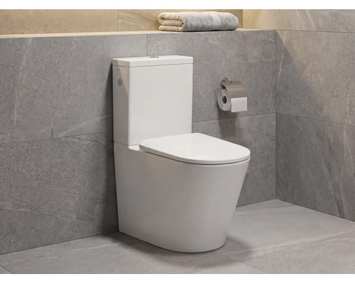 Modern staand toilet van keramiek met reservoir in een badkamer met grijze tegels met natuursteenlook.