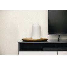 Lichtbeige vliesbehang met fijne linnenstructuur in een moderne woonkamer achter een tv-meubel met decoratie.